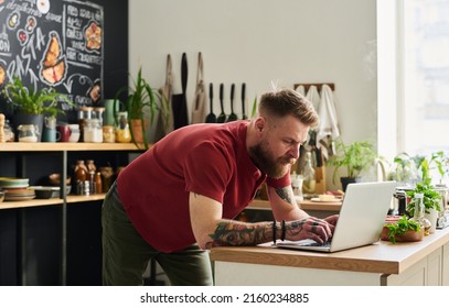 Young Man Using Laptop In Kitchen