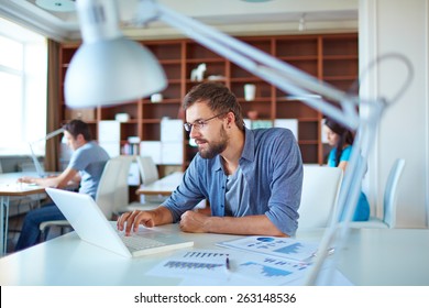 Young man using laptop in office - Powered by Shutterstock