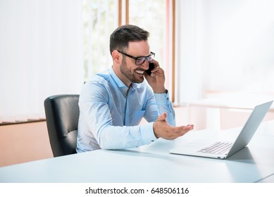 Young man using laptop and talking on the phone