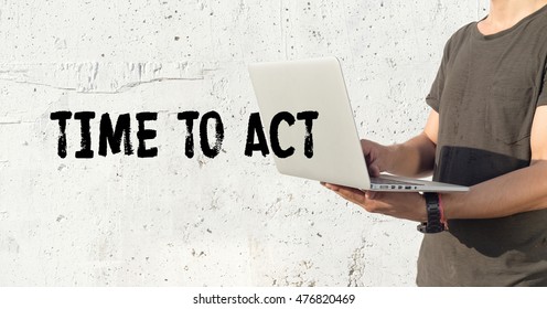 Young man using laptop and TIME TO ACT concept on wall background