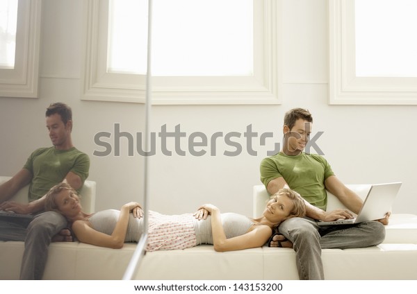 Young man using laptop with woman lying on his lap\
at home