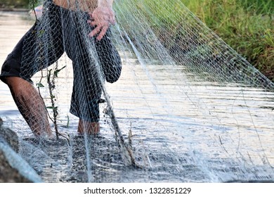 A young man is using mesh net to fish in swamps. - Shutterstock ID 1322851229