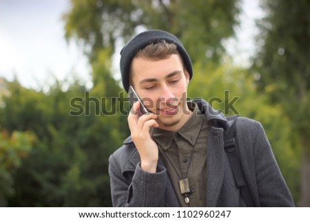 Young man using mobile phone in the city. Hipster and student lifestyle.