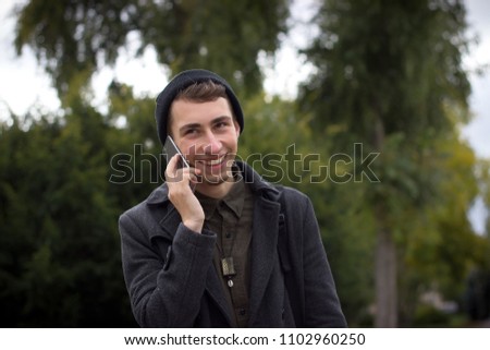 Young man using mobile phone in the city. Hipster and student lifestyle.