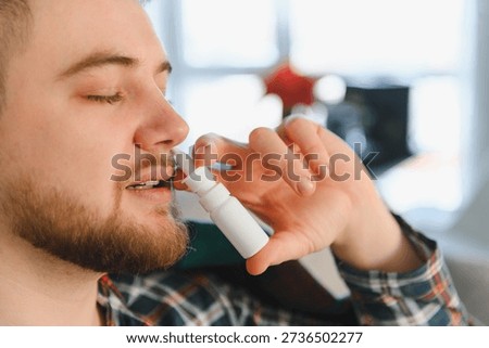 Young man using a nasal spray, managing symptoms of a cold, flu, or seasonal allergies. Finding relief from congestion