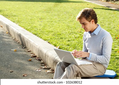 Young man using phone and laptop outdoors