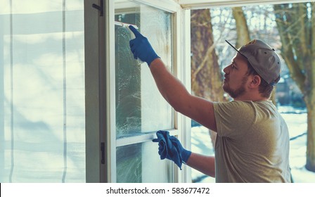 Young Man Is Using A Rag And Squeegee While Cleaning Windows. Professional Window Cleaner.