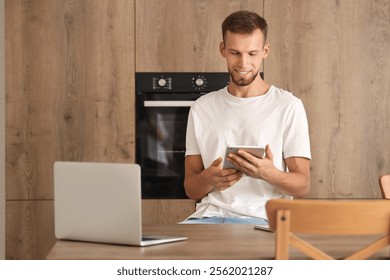 Young man using smart home control panel in kitchen - Powered by Shutterstock