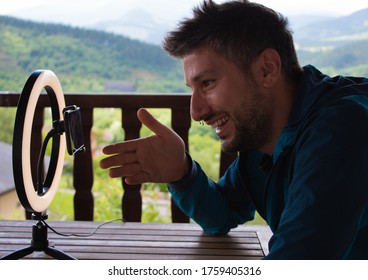 Young Man Using Smart Phone Camera In Front Of Ring Light, Recording Video.