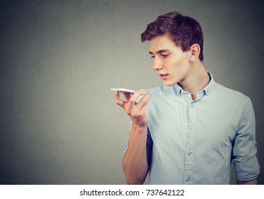 Young man using a smart phone voice recognition function isolated on gray wall background - Powered by Shutterstock