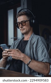 Young man using smartphone in hand, cafe, office,listening music on headphones, music streaming on smartphone, happy face, mp3, love sound, high fi less, dreams moods, concept, AirPods max, love,