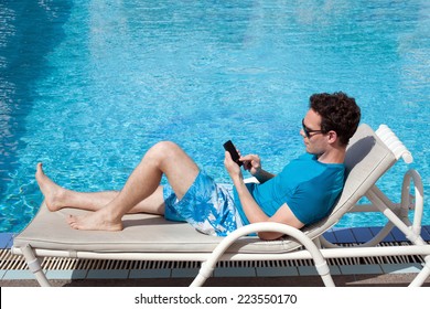 young man using smartphone near the pool in luxury hotel - Powered by Shutterstock