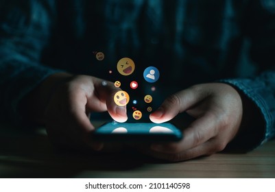 Young man using smartphone sending emojis, diverse positive emoji coming out of mobile phone. Mobile application for chatting, creative image, Social media concept.