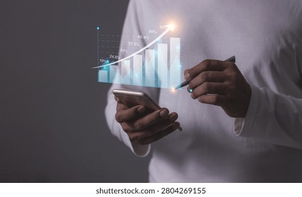 Young man using smartphone to visualize money growth The phone screen displays graphs and charts showing increasing investment and savings trends, along with an increased account balance