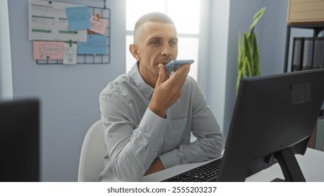 Young man using smartphone for voice command in modern office setting, surrounded by computer, plants, and strategic planning notes - Powered by Shutterstock