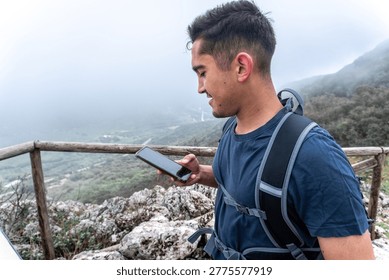 Young man using smartphone while hiking mountain trail