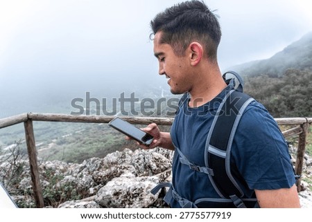 Young man using smartphone while hiking mountain trail