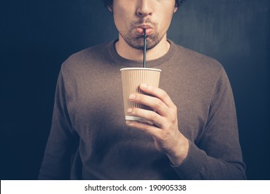 A Young Man Is Using A Straw To Drink From A Paper Cup