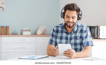 Young man using tablet computer and headphones at home - Powered by Shutterstock
