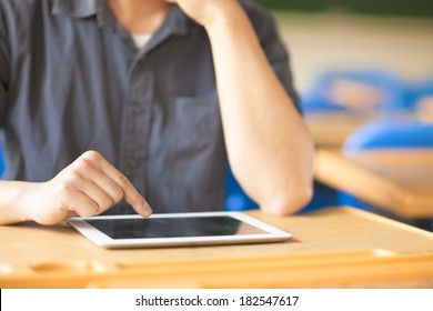 Young Man Using A Tablet Or Ipad In A Classroom