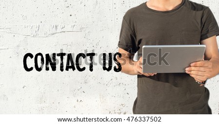 Young man using tablet pc and CONTACT US concept on wall background