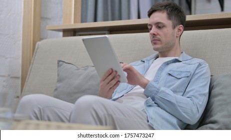 Young Man Using Tablet while Sitting on Sofa