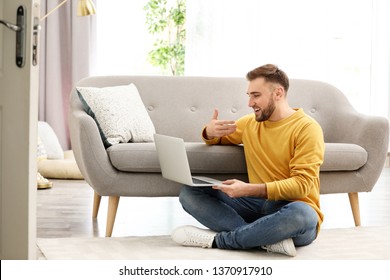 Young Man Using Video Chat On Laptop In Living Room