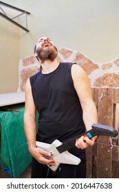 Young Man Using Video Game Toy Guitar To Simulate He Is Playing It