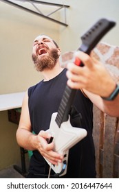 Young Man Using Video Game Toy Guitar To Simulate He Is Playing It