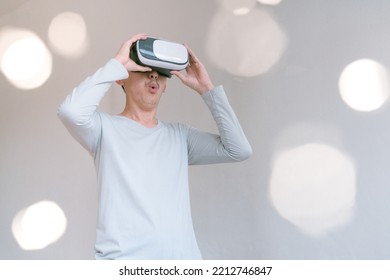 Young Man Using Virtual Reality Headset. Isolated On Grey Background Studio Portrait. VR, Future, Technology, Education Online, Studying . Man Trying To Touch Objects In Virtual Reality , 