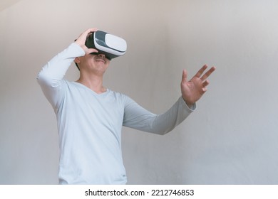 Young Man Using Virtual Reality Headset. Isolated On Grey Background Studio Portrait. VR, Future, Technology, Education Online, Studying . Man Trying To Touch Objects In Virtual Reality , 