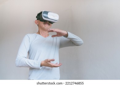 Young Man Using Virtual Reality Headset. Isolated On Grey Background Studio Portrait. VR, Future, Technology, Education Online, Studying . Man Trying To Touch Objects In Virtual Reality , 