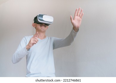 Young Man Using Virtual Reality Headset. Isolated On Grey Background Studio Portrait. VR, Future, Technology, Education Online, Studying . Man Trying To Touch Objects In Virtual Reality , 