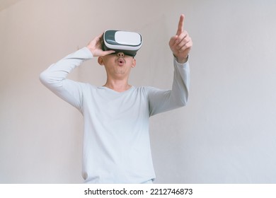 Young Man Using Virtual Reality Headset. Isolated On Grey Background Studio Portrait. VR, Future, Technology, Education Online, Studying . Man Trying To Touch Objects In Virtual Reality , 