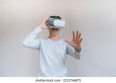 Young Man Using Virtual Reality Headset. Isolated On Grey Background Studio Portrait. VR, Future, Technology, Education Online, Studying . Man Trying To Touch Objects In Virtual Reality , 