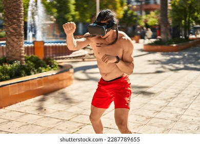 Young man using virtual reality glasses boxing at park