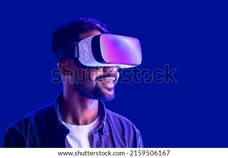 Young man using virtual reality headset. Isolated on blue background.