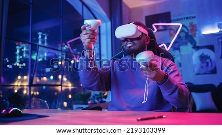 Young Man Using Virtual Reality Device with Controllers at Home in Loft Apartment. Stylish Black Male Browsing Online, Spending Time in VR Software and Digital Office. POV from Screen Perspective.