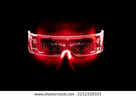 The young man is using virtual reality glasses. Portrait of man wearing backlit glasses while playing game.