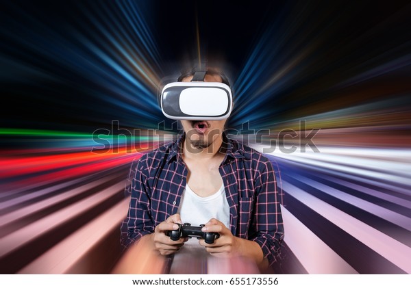 Young Man using Virtual Reality Glasses See a\
Simulation image 3D and Hands Holding a Joystick Controller while\
playing a video games