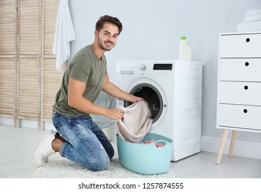 Young Man Using Washing Machine At Home. Laundry Day