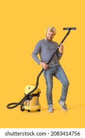 Young Man With Vacuum Cleaner Having Fun On Color Background