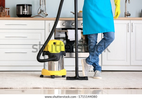 Young man with vacuum\
cleaner in kitchen
