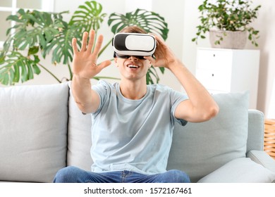 Young man with virtual reality glasses at home - Shutterstock ID 1572167461