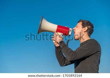young man voices to megaphone warning of dangerous event. Copy space