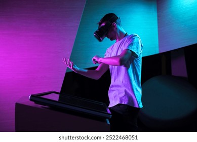 Young man with a VR headset having an immersive virtual reality experience in a room with purple lighting, making various hand movements in the air.