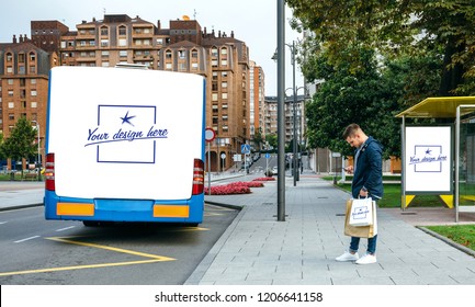 Young man waiting for the bus while looking at the mobile. Customizable rear end of bus, shopping bag and bus canopy