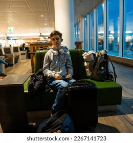 A young man waits for his flight to be announced at an airport - Shutterstock ID 2267141723