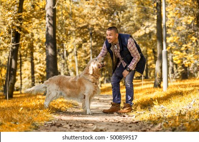 Young man walking a dog at the park in good weather. Boy and golden retriever.