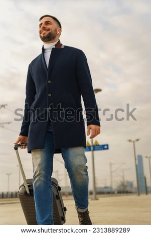 Young man walking down a train station with his suitcase in hand, he's going on a business trip. low angle shot